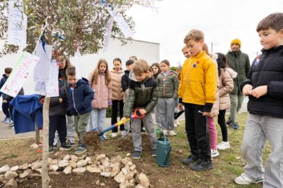 Les enfants devant l'olivier planté, un enfant verse de la terre avec une pelle - Agrandir l'image, fenêtre modale