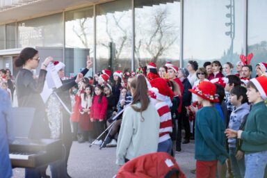 Les enfants chantent, en tenue de Noël sous la direction de leur enseignante